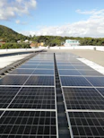 A rooftop solar panel installation gleaming under a clear blue sky.