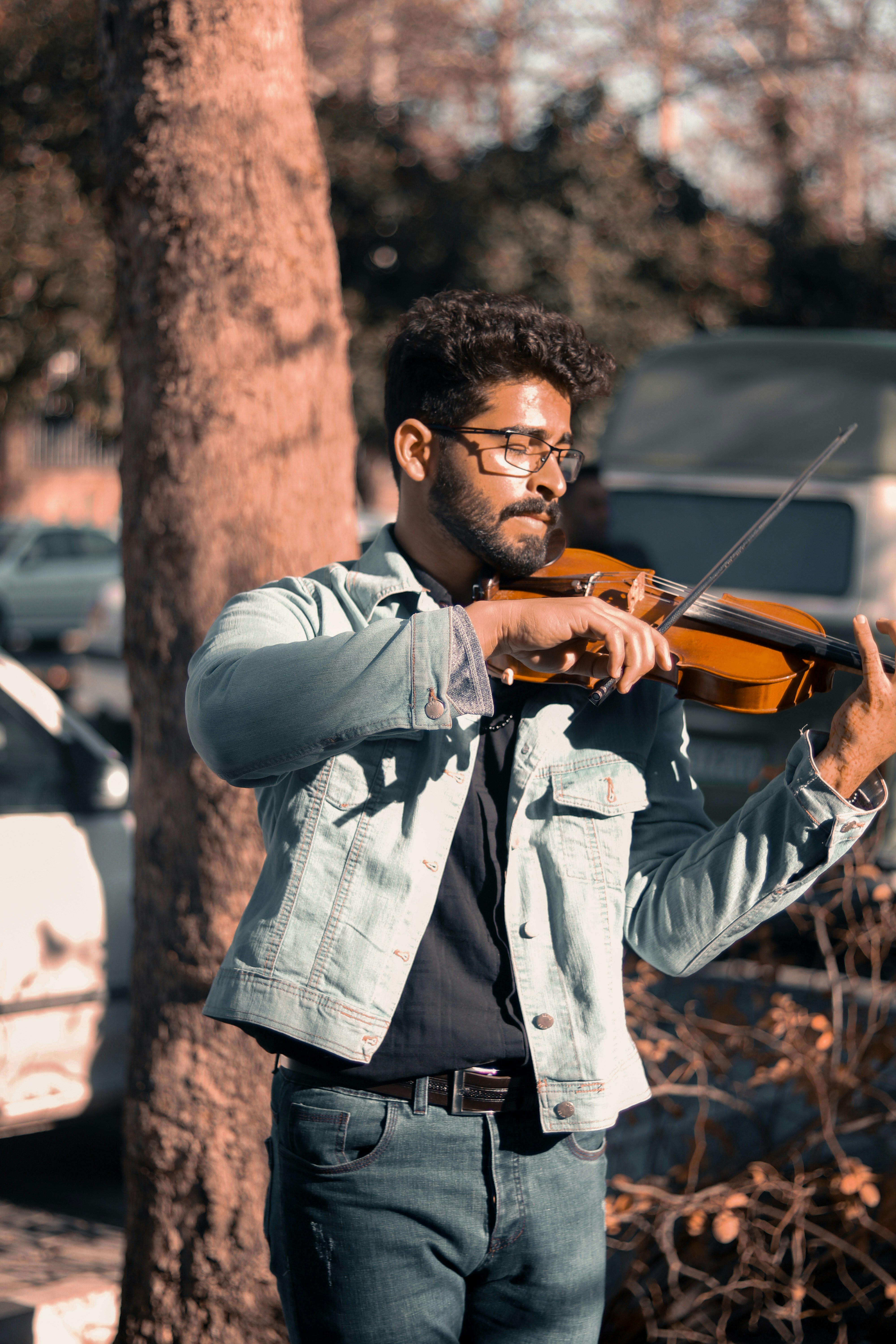 a man playing a violin in front of a tree