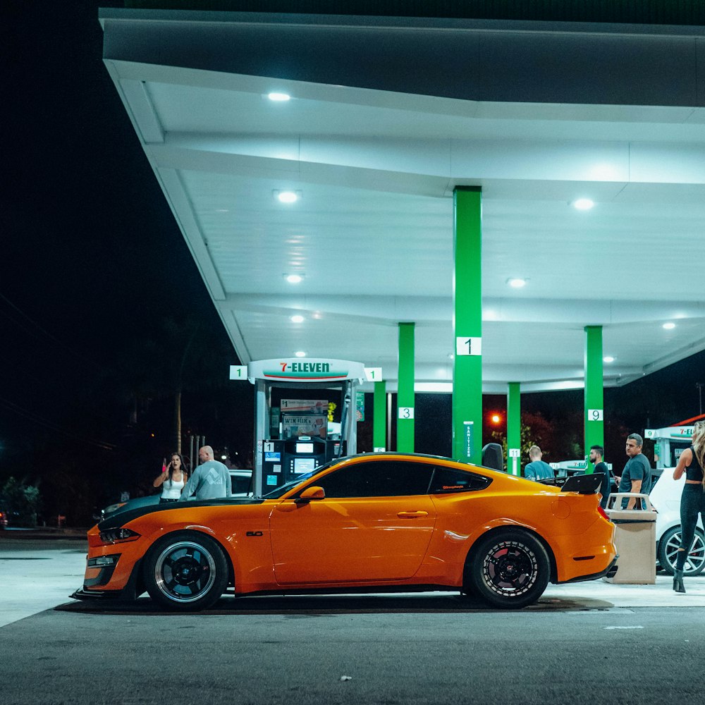 a bright orange sports car parked at a gas station