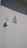 A white wall features a doorbell with a sign next to it that says 'BELL' and an arrow pointing to the push button. Above, there are metallic house numbers and a letter 'B 38'. The shadow of the lettering is visible on the wall.