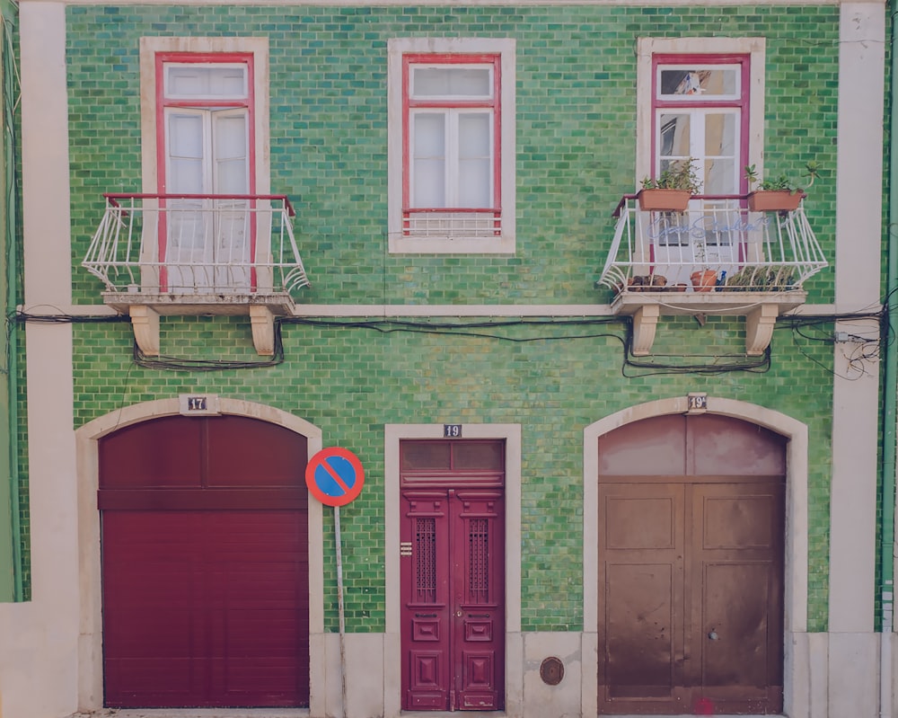 a green building with two red doors and a blue sign