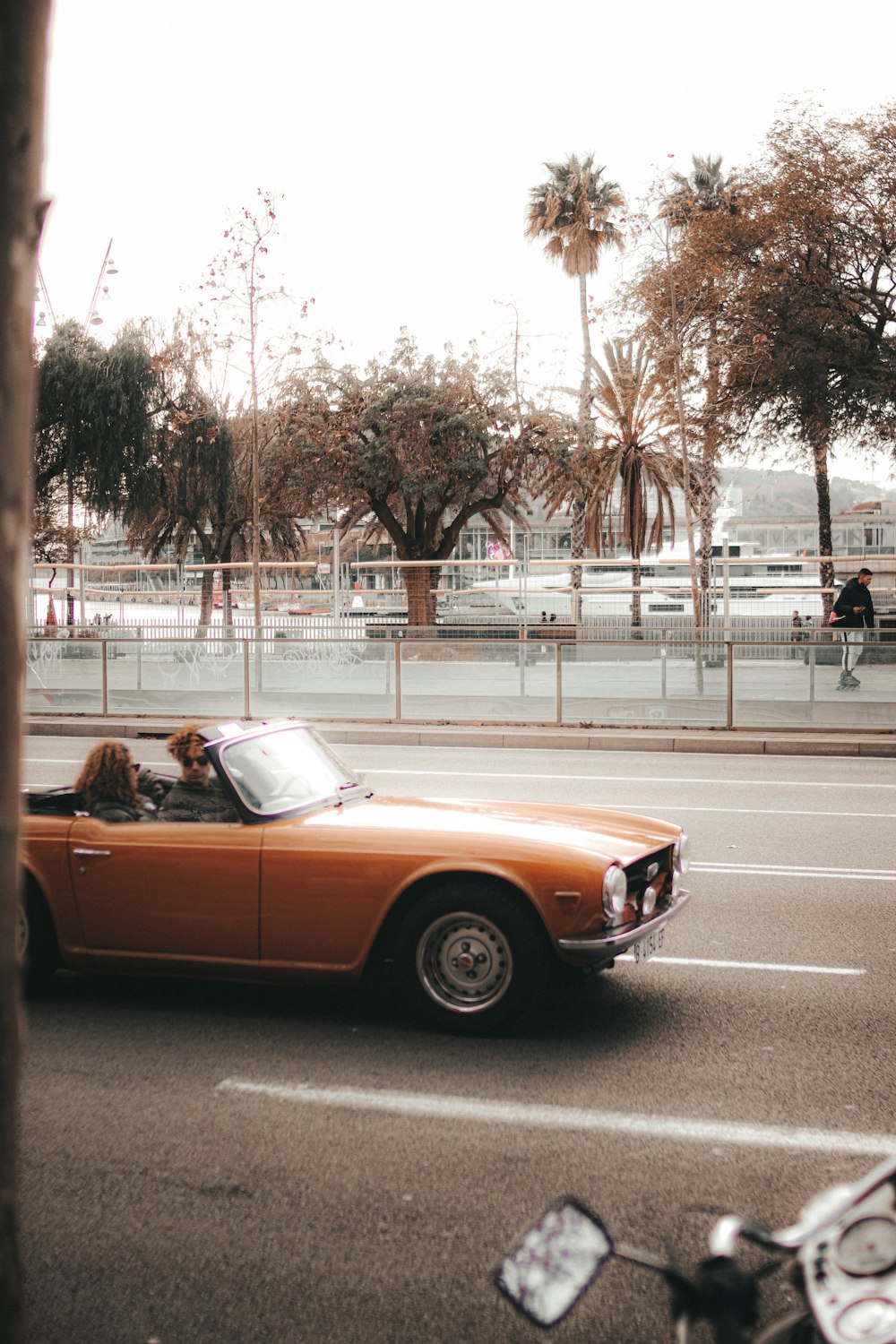 an orange convertible car driving down a street