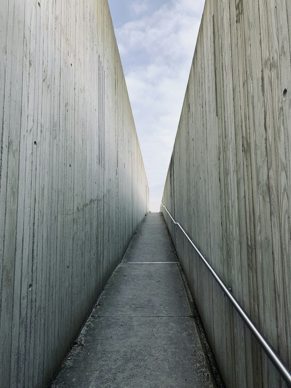 a long narrow walkway between two concrete walls