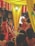 A wedding ceremony with several people dressed in traditional attire. The setting includes vibrant colors with yellow drapes and red and white flower decorations. A man is seated on a throne-like chair wearing ceremonial clothing and a turban, while a woman in a red saree stands nearby. The ambiance is festive, with other people surrounding the scene.
