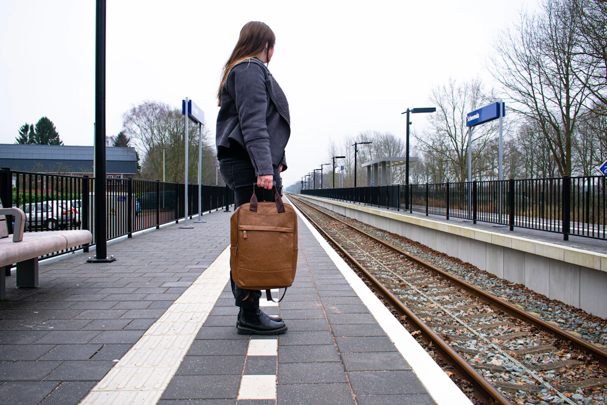 Seorang perempuan membawa koper menunggu kereta di stasiun