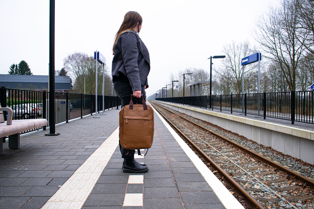 a woman with a suitcase waiting for a train