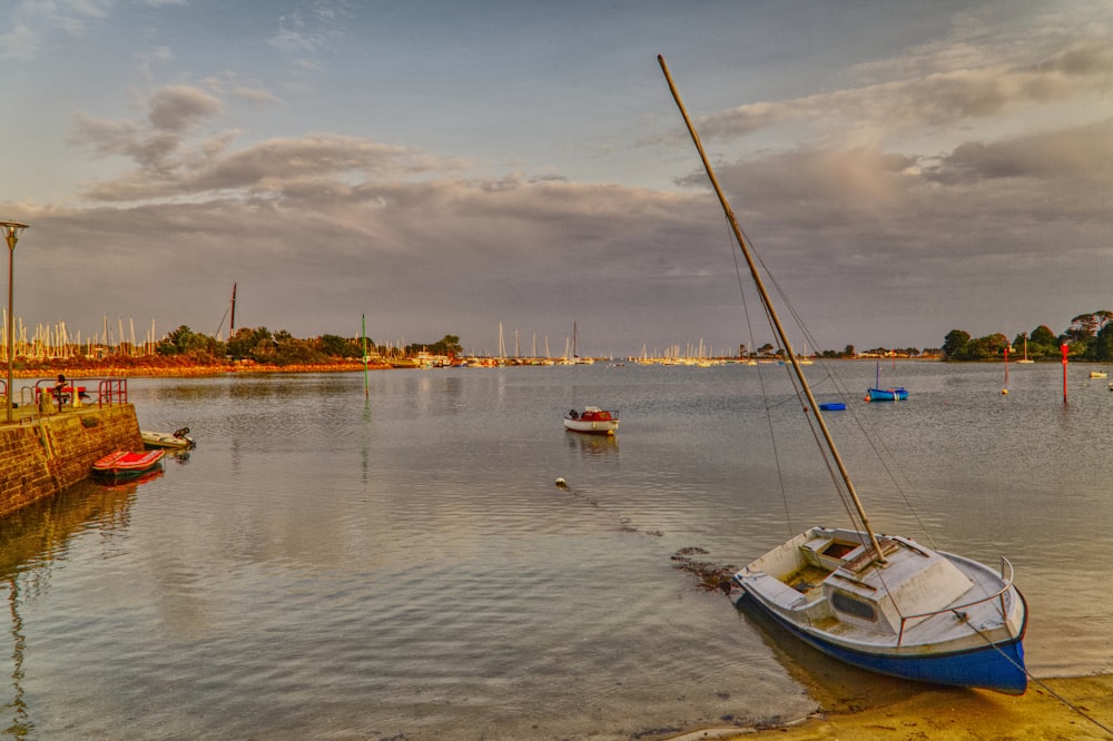 a sailboat is sitting in the water next to a dock