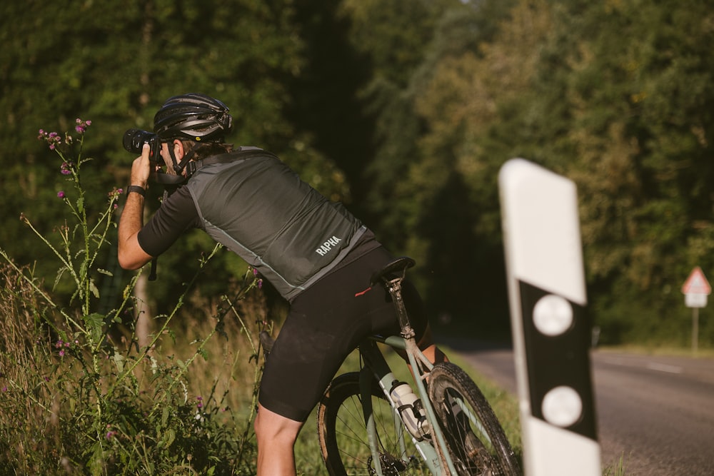 a man riding a bike down a road next to a forest