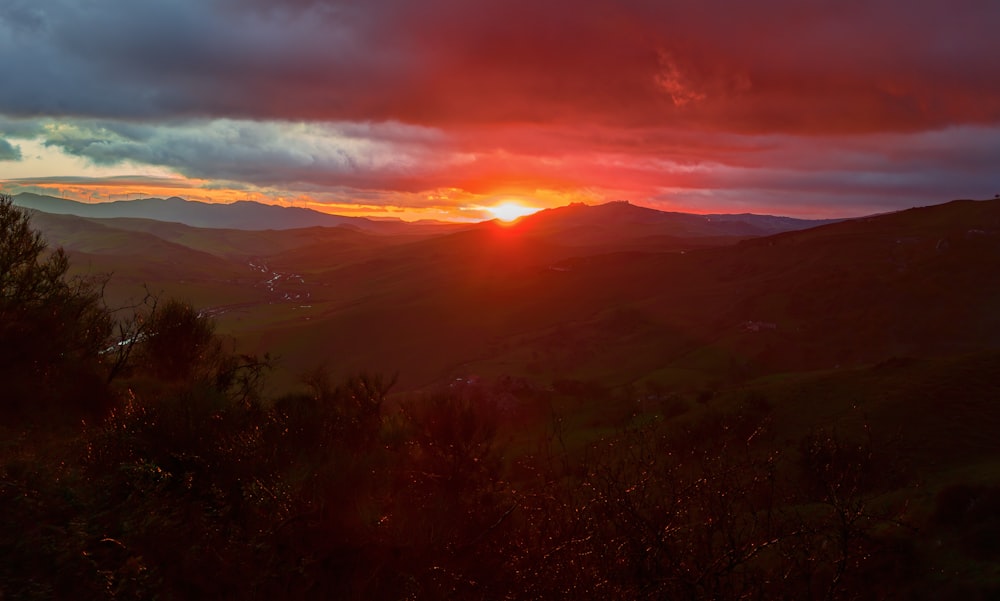 the sun is setting over a mountain range