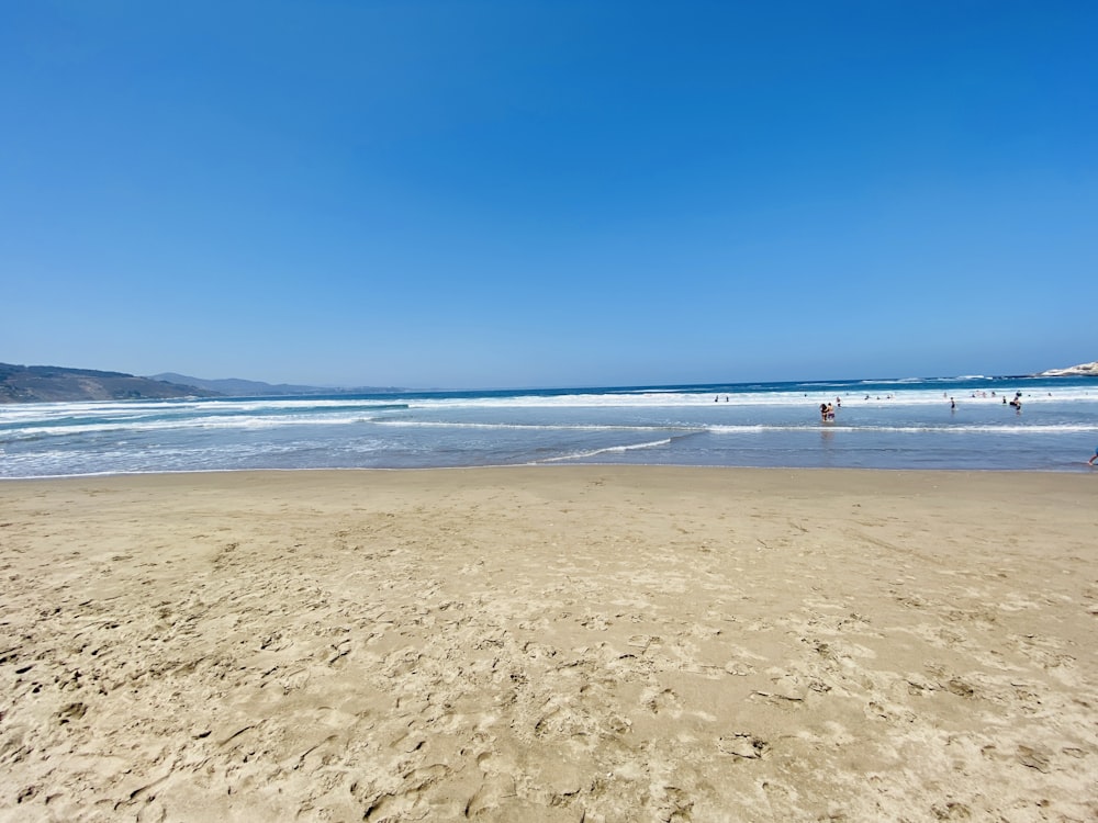 a sandy beach with people in the water