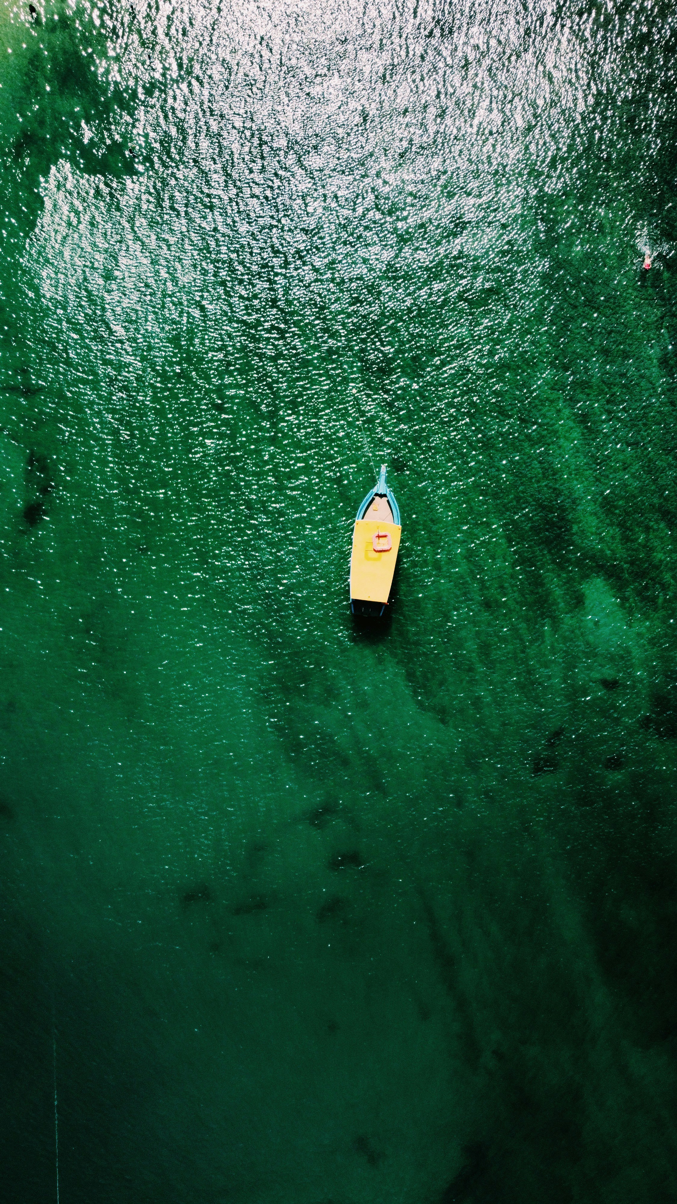 A small yellow boat floating on top of a body of water photo – Free ...
