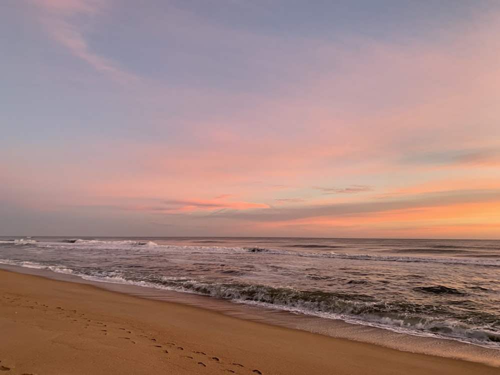 a person walking on a beach with a surfboard