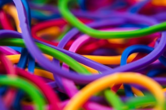 Vibrant, colorful loops intertwined in a chaotic manner, creating a lively and dynamic visual effect. The loops are primarily composed of rubbery textures and feature a diverse range of bright colors.