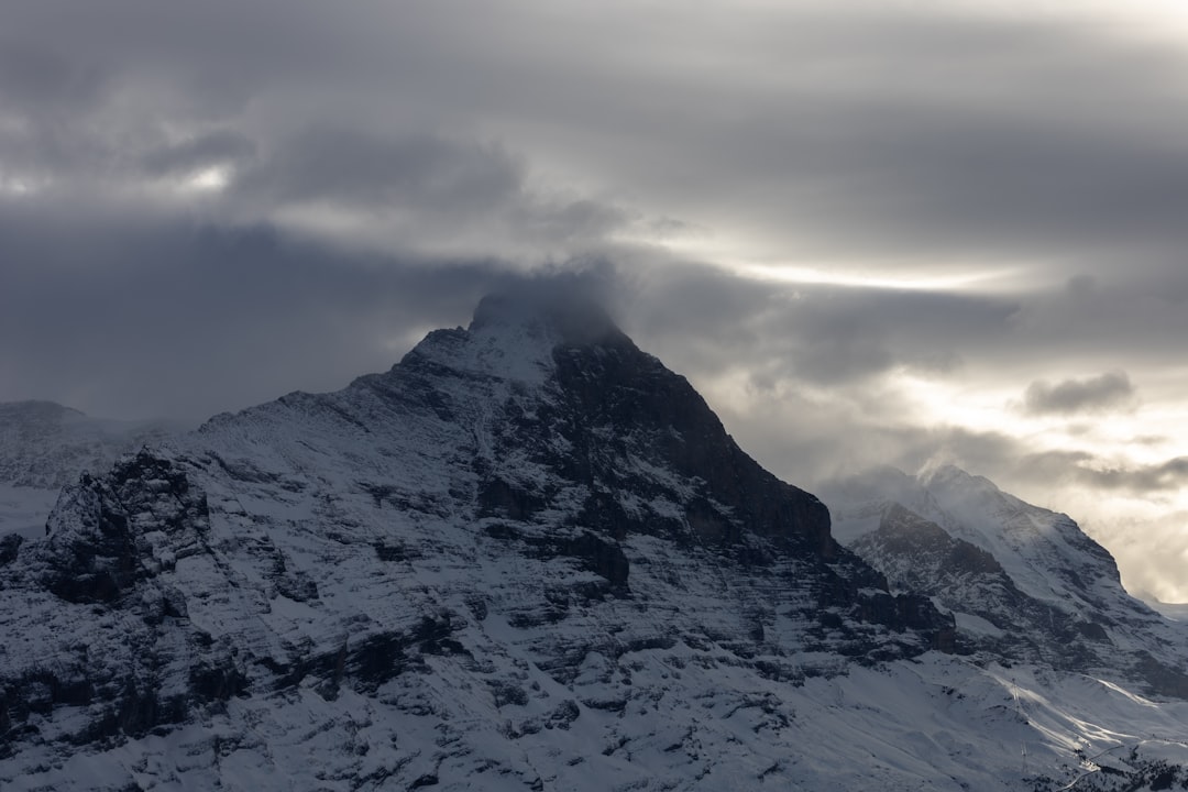 a large mountain covered in snow under a cloudy sky,