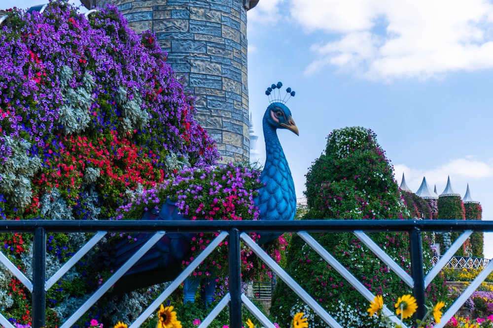 a peacock statue sitting on top of a metal fence