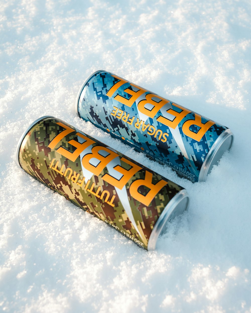two cans of beer sitting in the snow