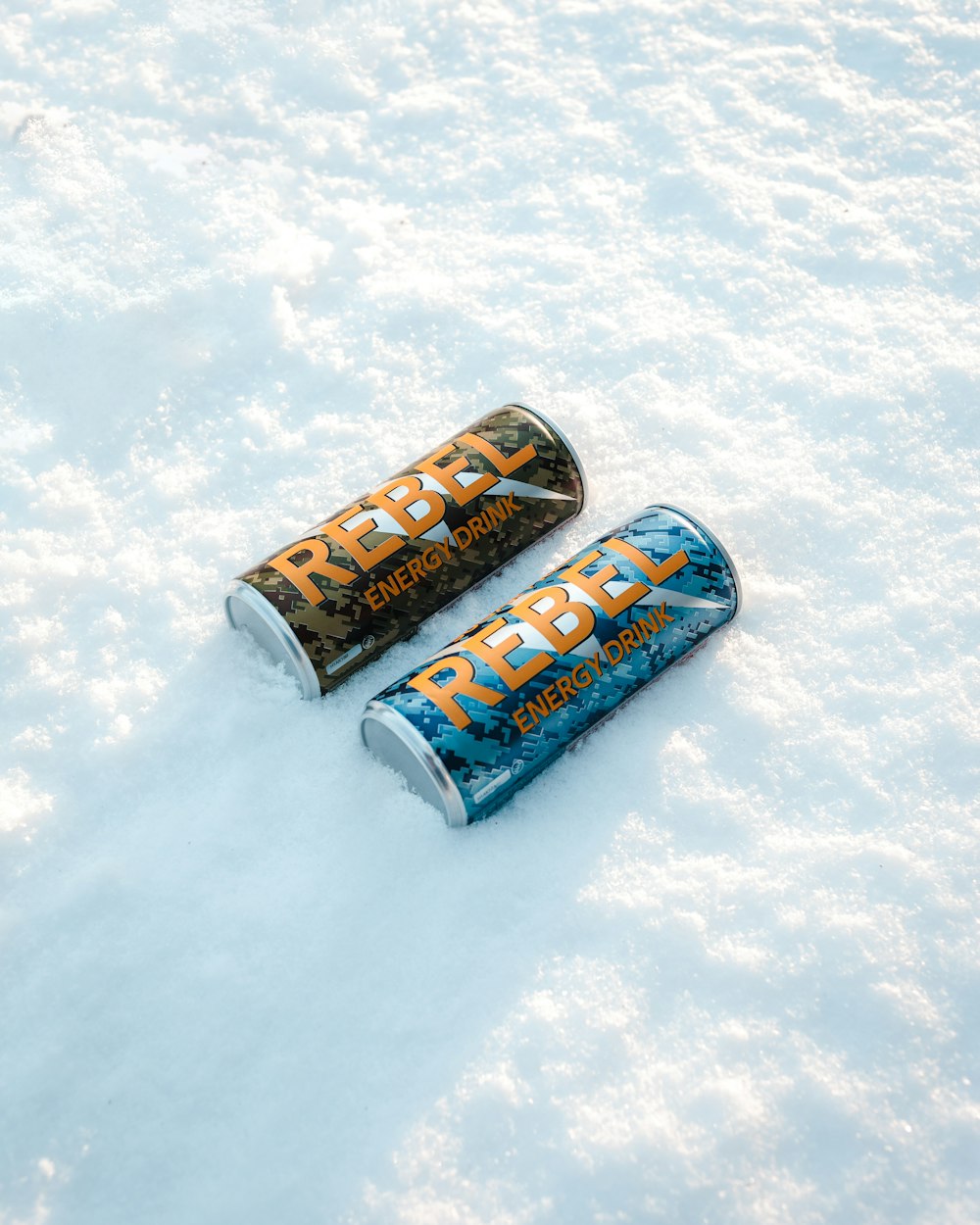 two cans of energy drink sitting in the snow