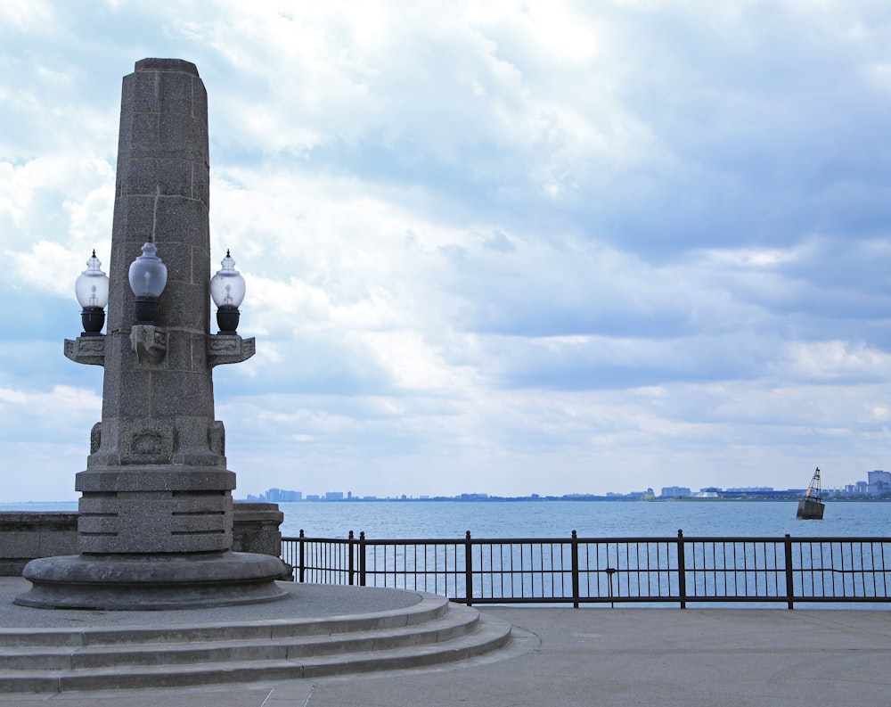 a monument with a clock on it near the water