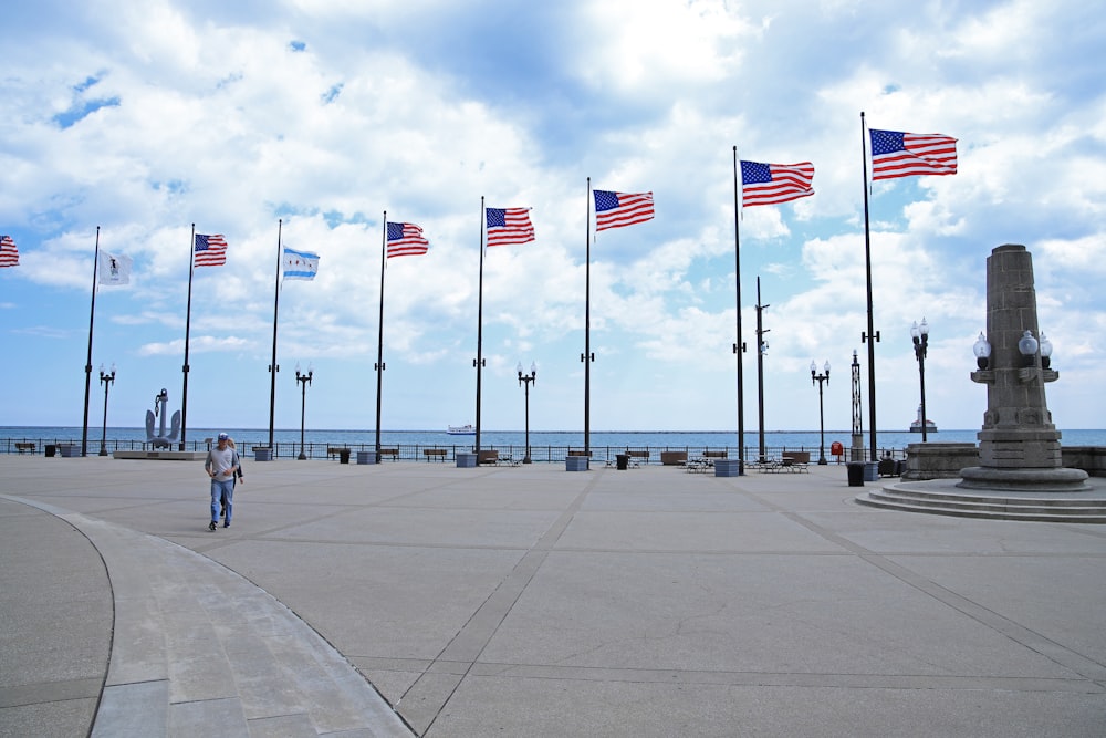 a man walking down a sidewalk next to a bunch of american flags
