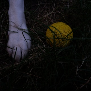 A close-up of a pétanque ball on a sandy court.