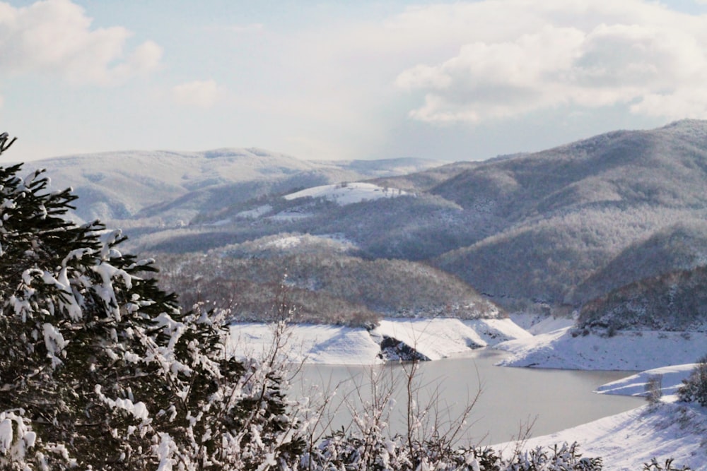 a view of a lake surrounded by snow covered mountains