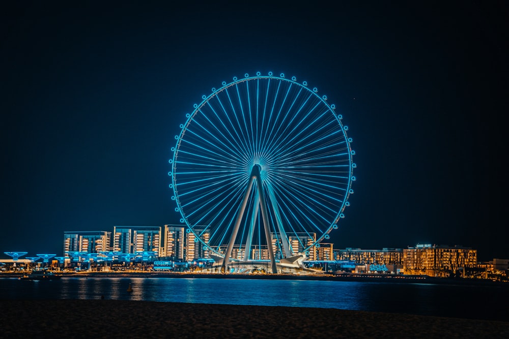 a large ferris wheel sitting above a city at night