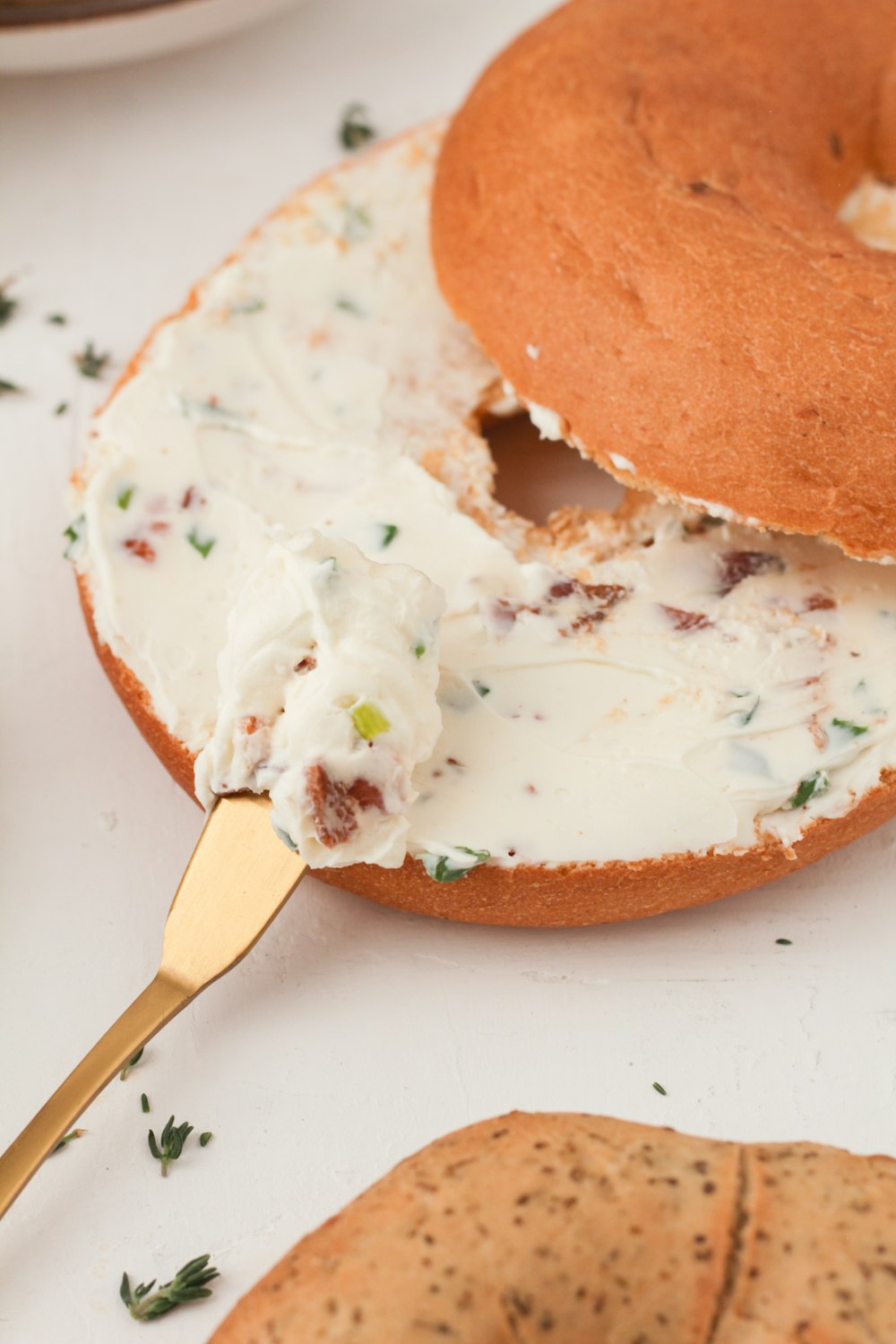 a bagel with cream cheese and a golden spoon