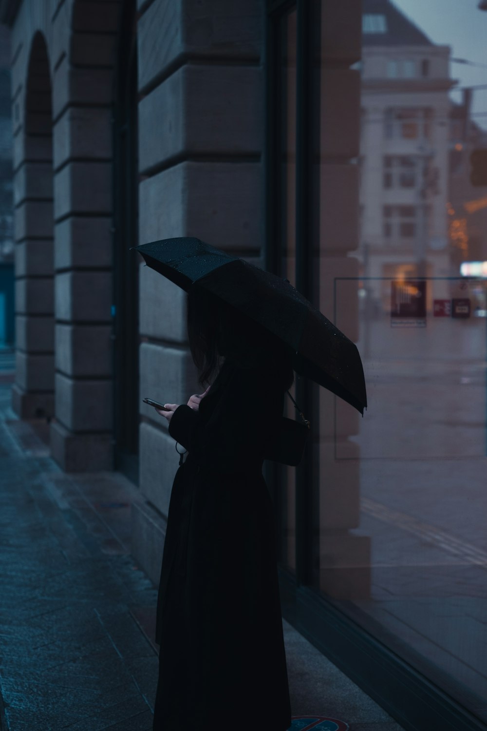 a woman standing on a sidewalk holding an umbrella