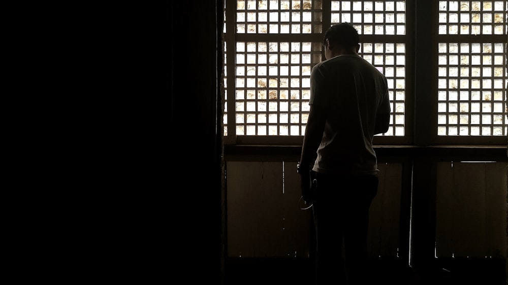 a man standing in front of a window in a dark room