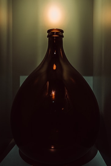 Elegant close-up of a glass bottle with natural oil surrounded by olive leaves and soft golden light