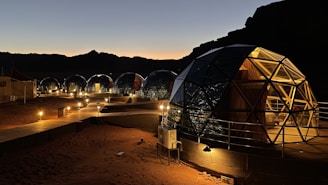 Illuminated dome village at night surrounded by nature, evoking peace and exclusivity.