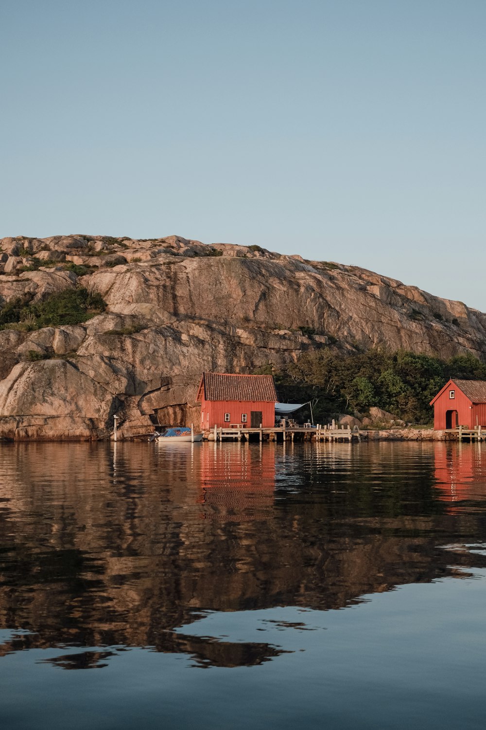 a red house sitting on top of a lake next to a mountain