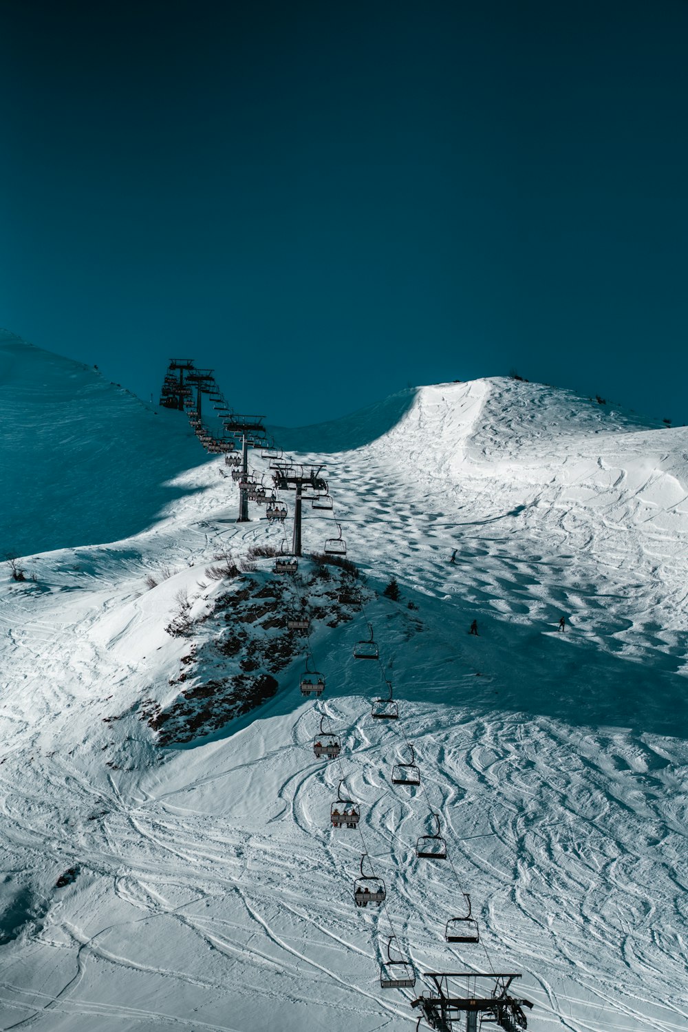 a ski lift going up the side of a snow covered mountain