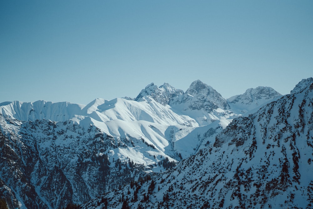 a mountain range covered in snow under a blue sky