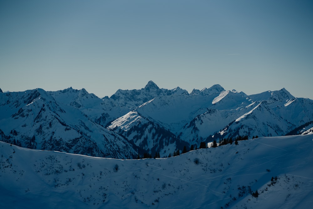 a mountain range covered in snow under a blue sky