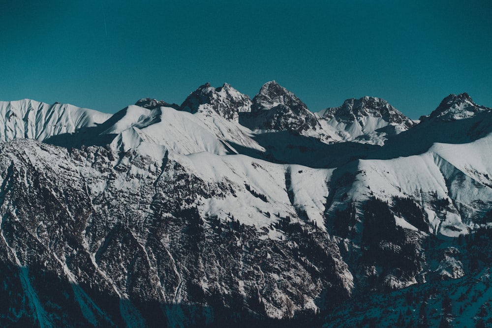 a snow covered mountain range under a blue sky