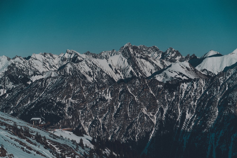 a snow covered mountain range with a house in the foreground