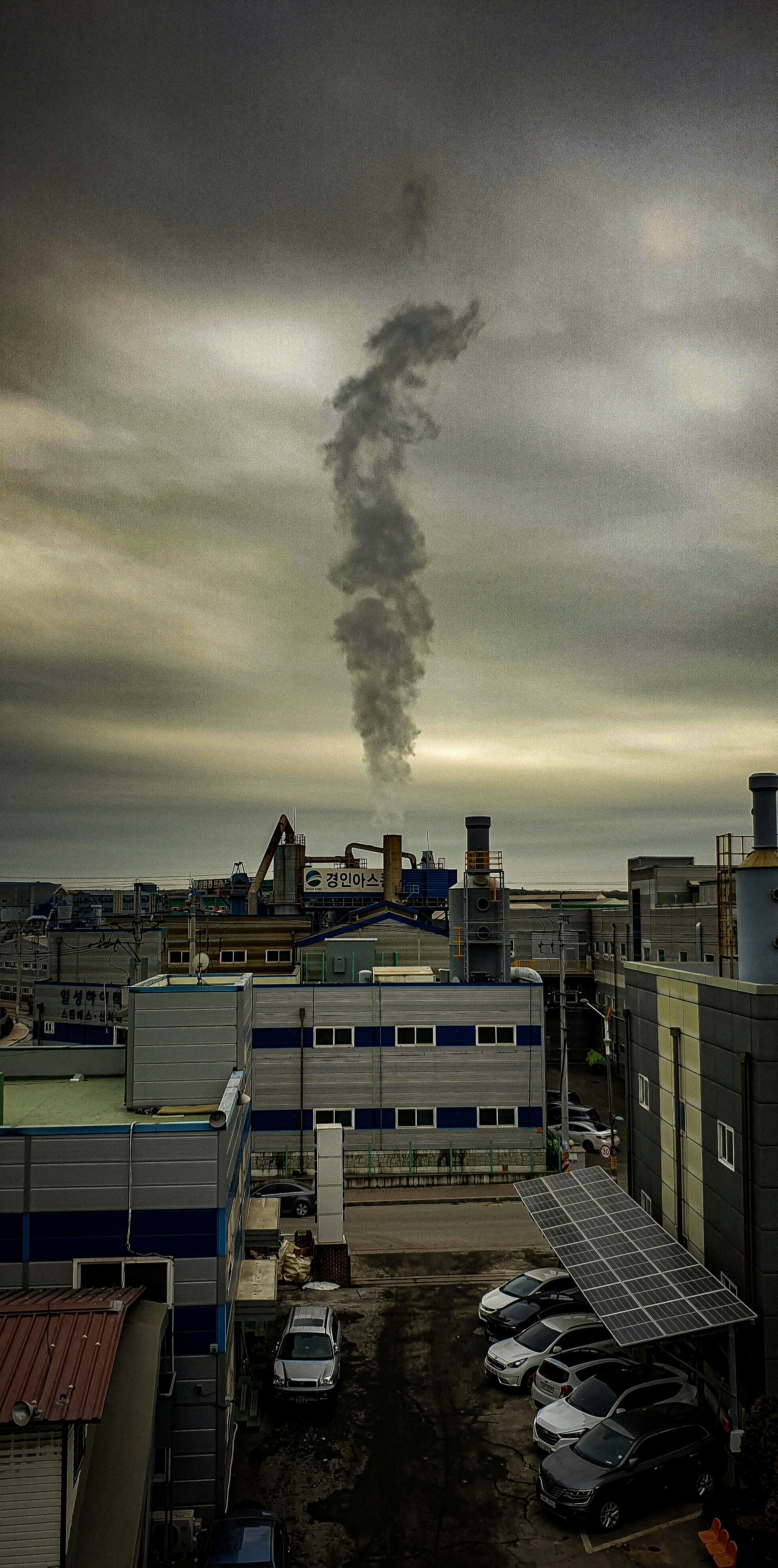 a smokestack billows from a building in a city