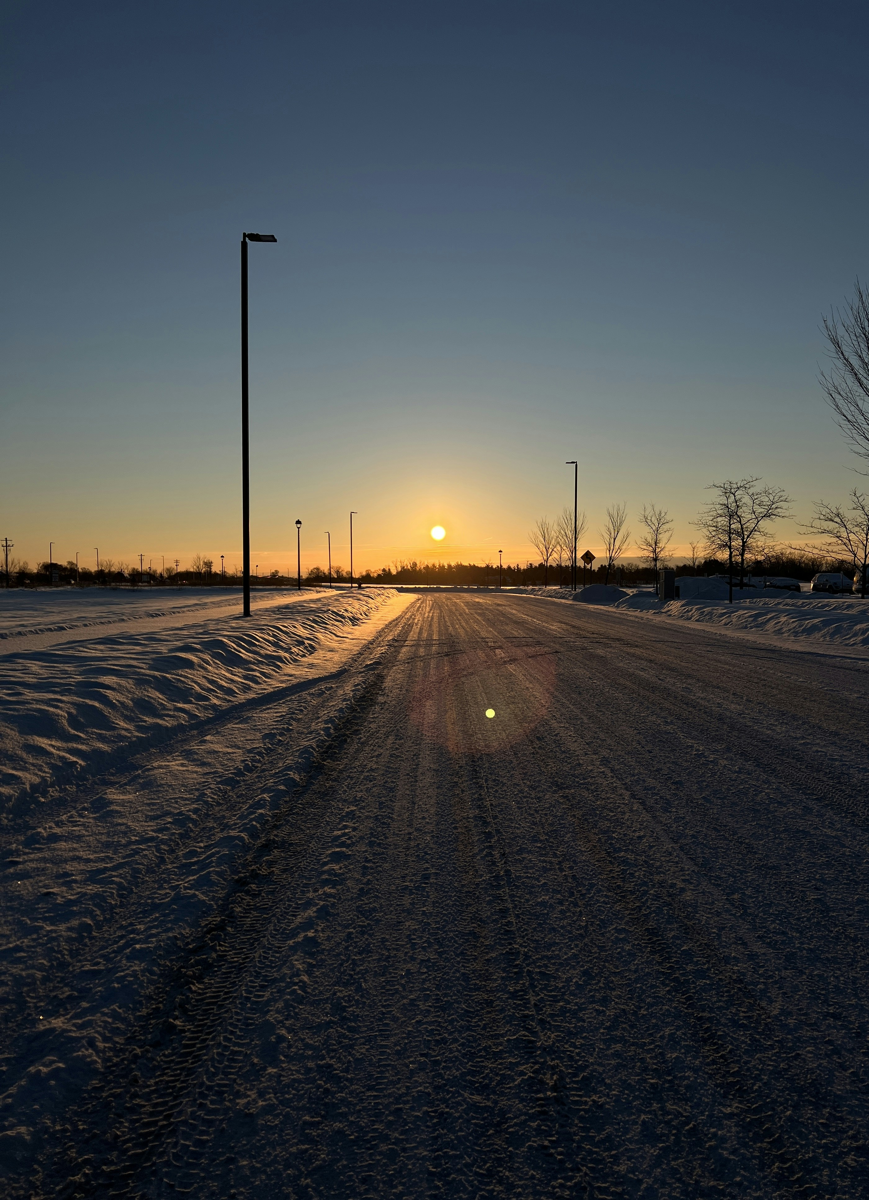 Die Sonne geht über einer verschneiten Straße unter