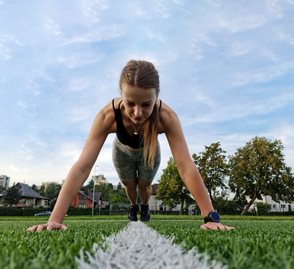 a woman is doing push ups in the grass