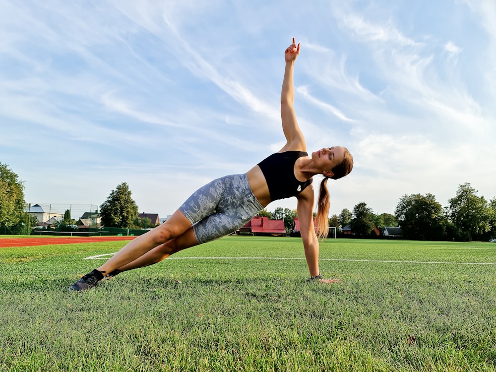 a woman doing a yoga pose in a field