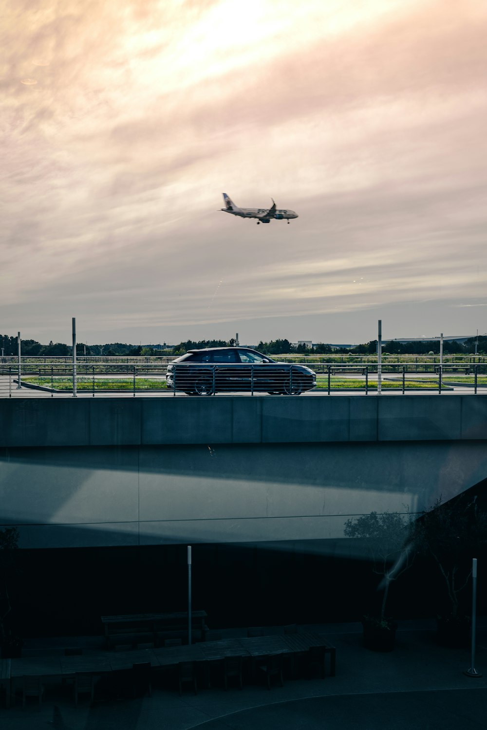 an airplane is flying over a bridge and a car