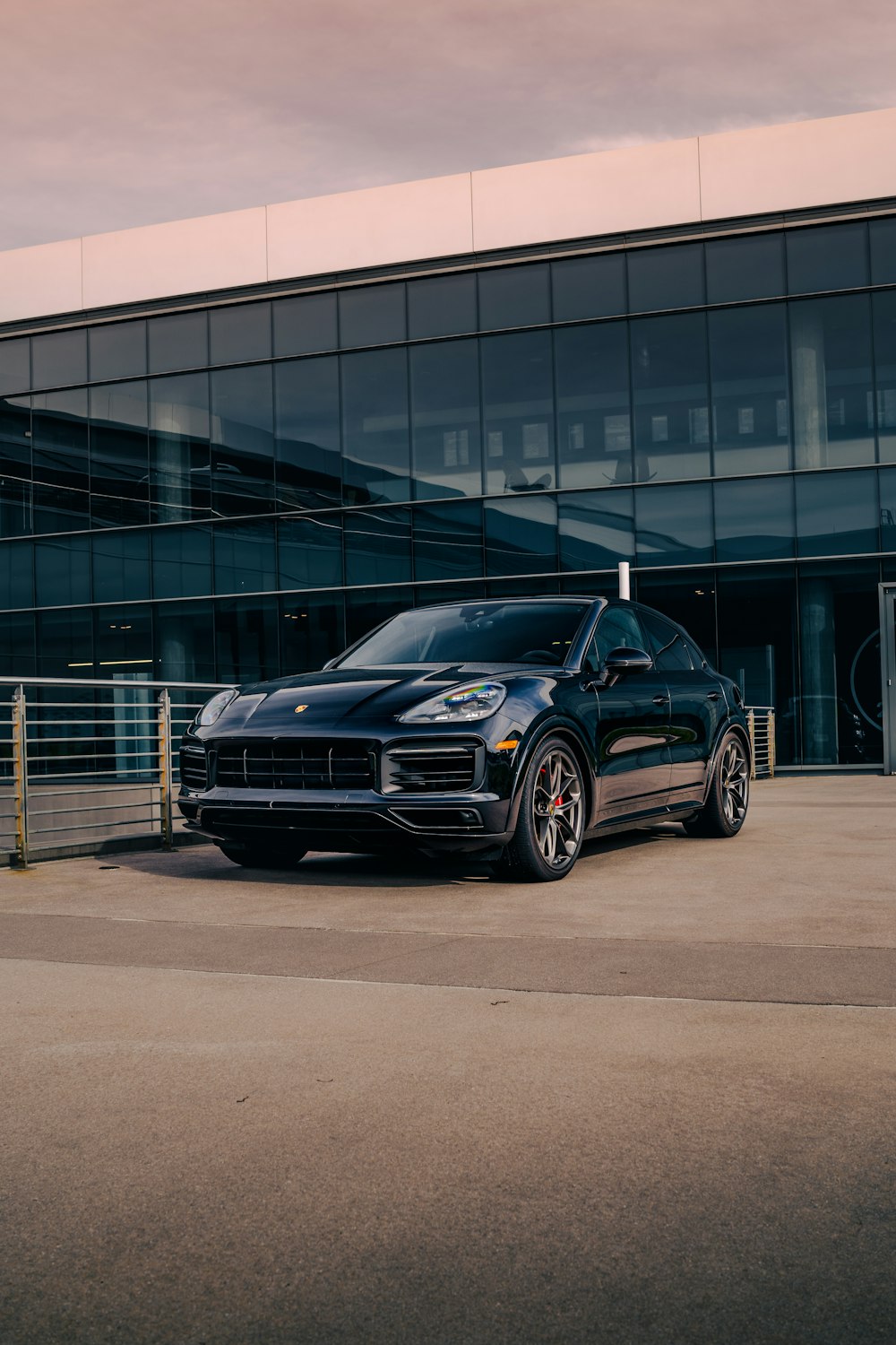 a black porsche cayen is parked in front of a building