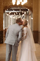 Bride and groom sharing a tender slow-motion kiss under soft blush pink lighting.