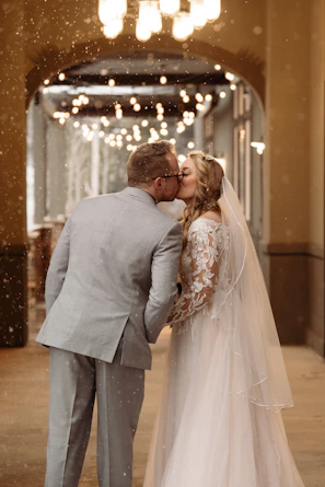 Bride and groom sharing a tender slow-motion kiss under soft blush pink lighting.