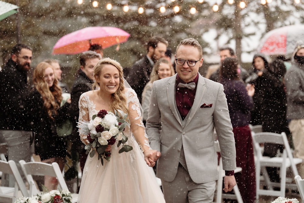 a bride and groom walking down the aisle in the rain