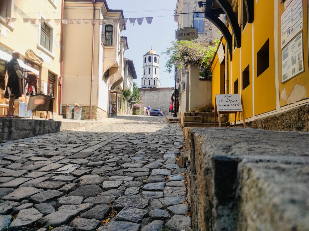 a cobblestone street with a clock tower in the background