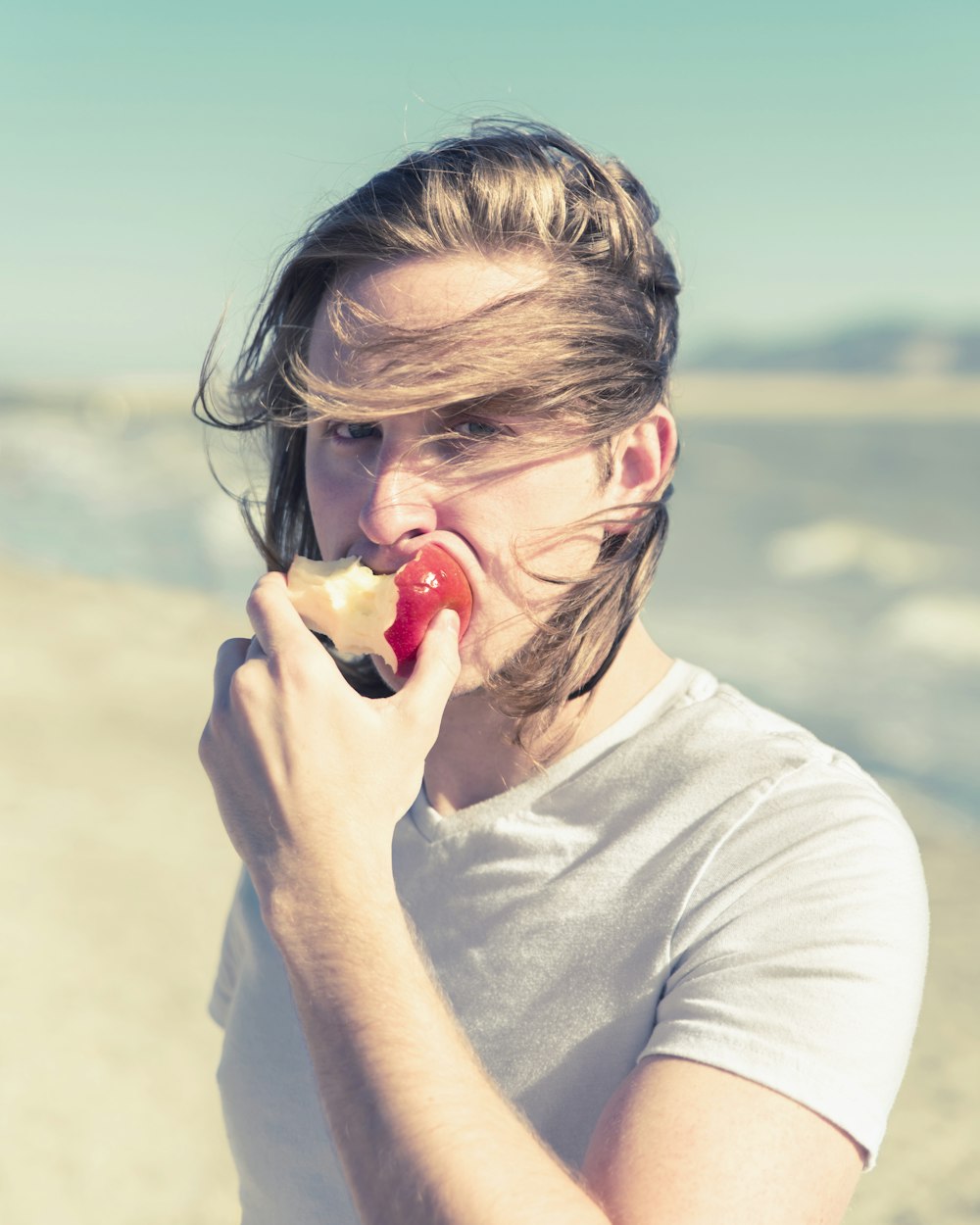 a woman eating an apple on the beach