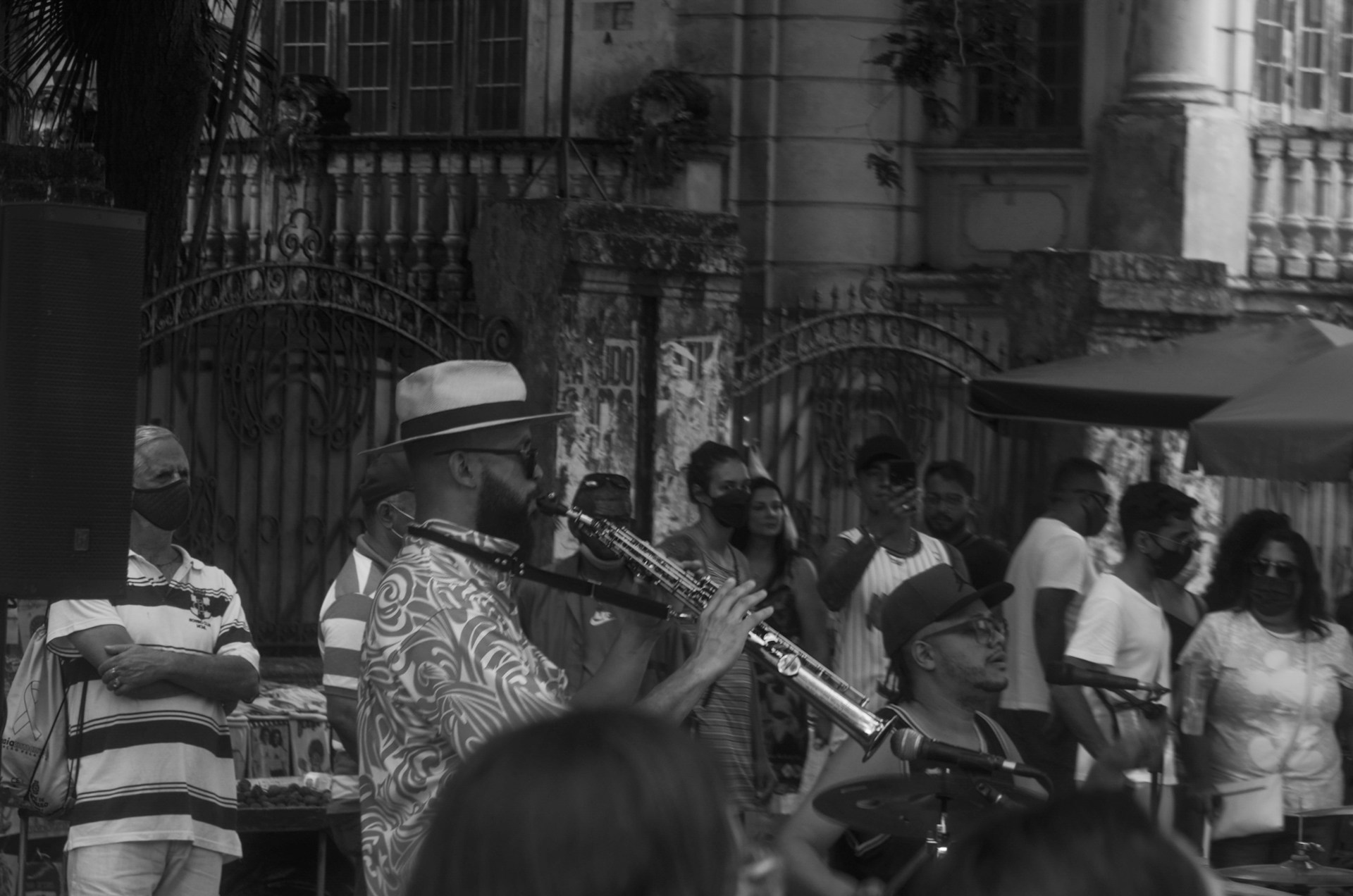 A lively outdoor celebration with a saxophone player entertaining a happy crowd.