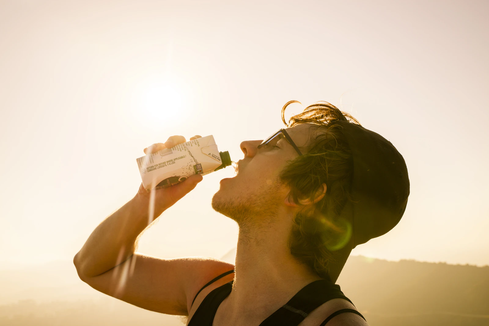 Hombre bebiendo agua de una botella durante una ruta de senderismo